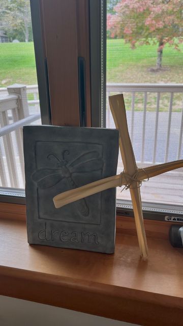A wooden cross and a book on a windowsill.